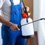 Pest control technician spraying indoor treatment near windows and baseboards in {city}, {state}